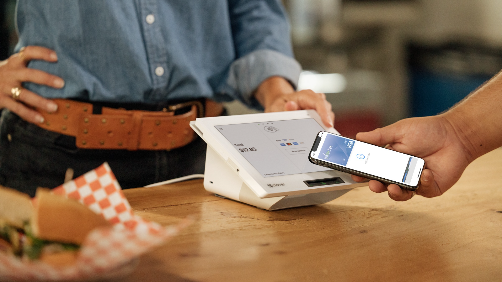 Customer buying lunch with their NexTier Digital Debit Card at a Clover Merchant Service restaurant.